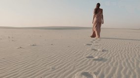 A woman in a flowing pink dress walks barefoot across vast white sand dunes, leaving footprints behind. The serene landscape and soft light create a peaceful, cinematic, and elegant visual. - Powered by Shutterstock - Get 15% off with code: PIKWIZARD15
