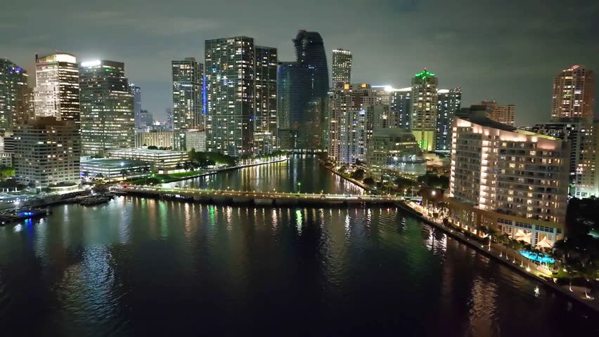 Aerial Shot Of Illuminated Bridge Amidst Buildings Against Sky Drone Flying Forward Over Sea Near City At Dusk Miami Florida.