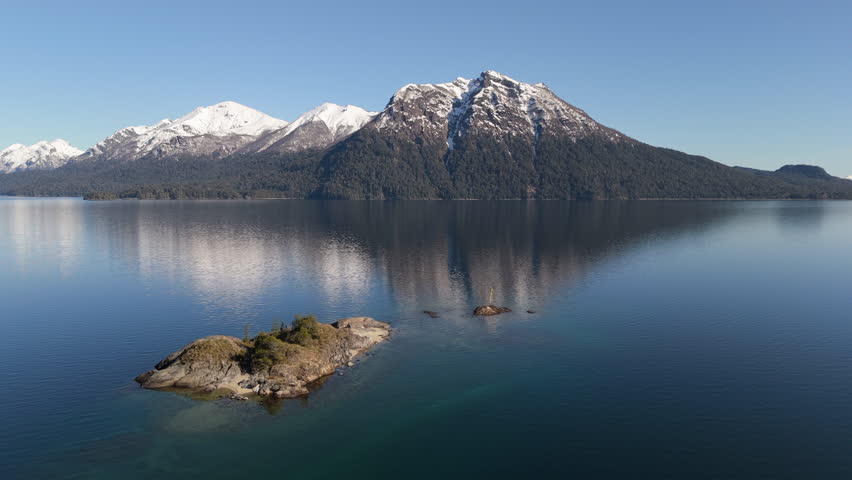 Crystal clear water of Lake Nahuel Huapi reflects snow-capped peaks of Andes. Bariloche, Argentina.