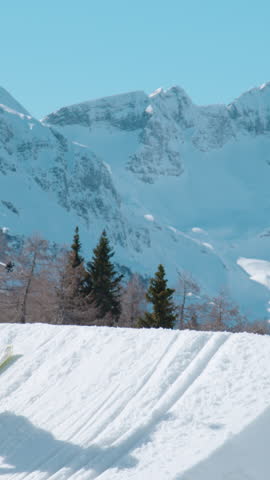 VOGEL, BOHINJ, JULIAN ALPS, SLOVENIA, MARCH 2022: SLOW MOTION: Male freestyle skier flying above snow-covered mountaintops. Extreme athlete rotating through the air and performing grab trick.