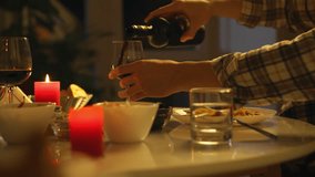 A hand pours red wine into a glass at a dinner table adorned with candles and various dishes. The soft lighting creates a cozy atmosphere, perfect for a relaxed evening meal - Powered by Shutterstock - Get 15% off with code: PIKWIZARD15