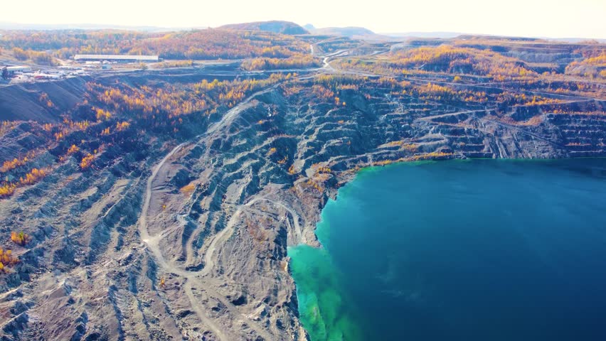 Aerial orbit of Black Lake with turquoise waters and rugged mining terrain