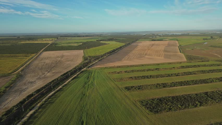 Long train track cutting through fields in rural Velddrif, South Africa, aerial view