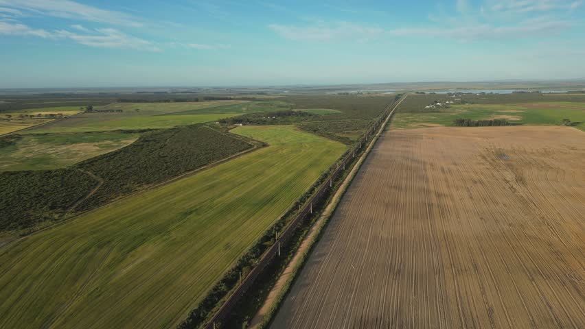 Long train track cutting through fields in rural Velddrif, South Africa, aerial view