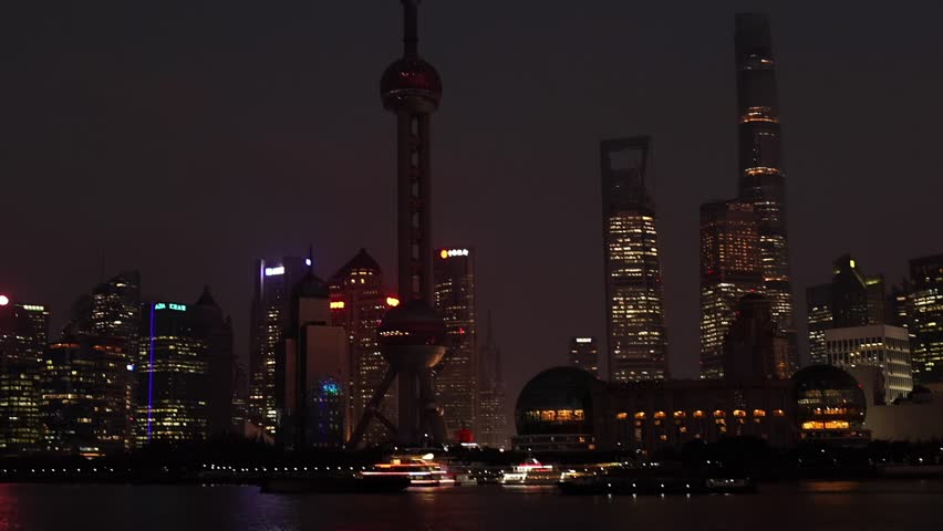 Night view Shanghai city with illuminated skyline, Oriental Pearl Tower and scyscrappers, reflecting on water of Huangpu river. Vibrant and modern cityscape in the evening. Travel destination