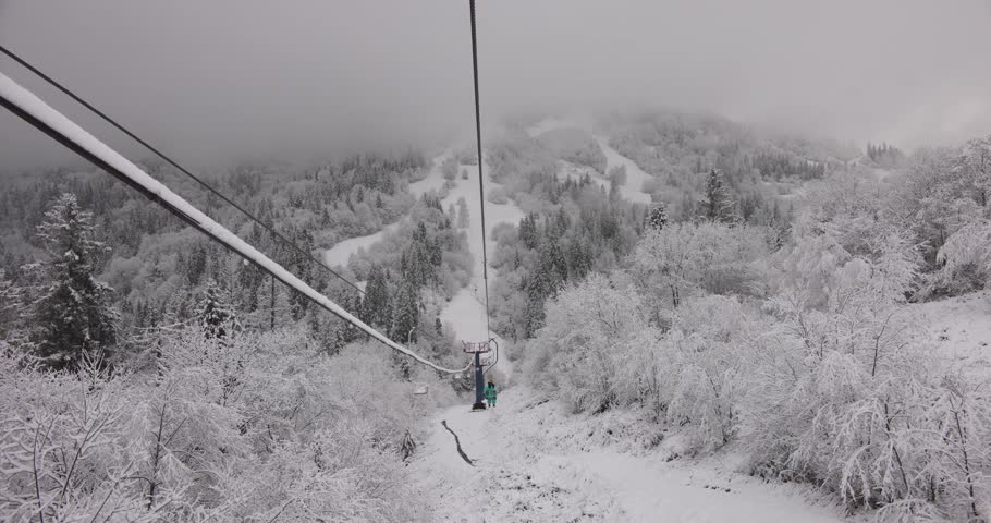 A stunning winter scene captured from a funicular ride overlooking a snow-covered mountain forest and ski slopes. The serene landscape features frosted trees and peaceful winter beauty.
