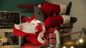 Santa Claus sits in a chair, using his laptop to stay connected - Powered by Shutterstock - Get 15% off with code: PIKWIZARD15