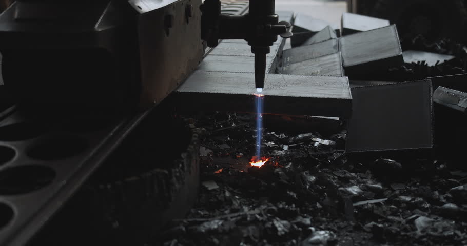 Elevated view of a plasma cutter slicing through a metal plate with precision. Sparks and molten edges highlight the detailed machinery and cutting process in a professional setup.