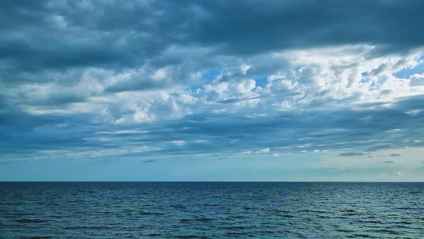 Black Gray White Storm Cumulus Clouds in Blue Sky over the Ocean in Sun Rays Horizon. Beautiful Aerial View of Cloudy Sky and Sea. Planet, Bay Sky and Rain Clouds Background, Travel, Vacation Journey.
