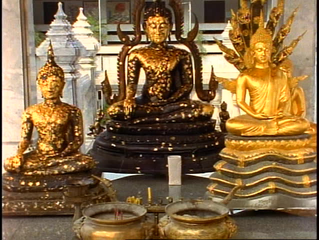 Three Buddha statues in a shrine, medium close up