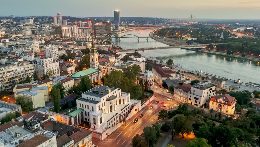 Aerial perspectives of Belgrade, Serbia as the sun sets, illuminating the vibrant skyline and reflecting on the tranquil waters of the River Sava