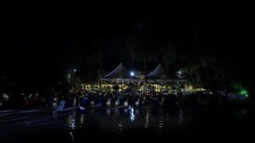 Aerial panoramic night view of a resort with a swimming pool, decorative lights, and a crowd gathered for an event. wedding concept.event management concept - Powered by Shutterstock - Get 15% off with code: PIKWIZARD15