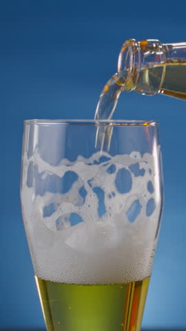 Beer is poured into a glass from a bottle. It's a traditional low-alcohol drink that many people love.vertical video