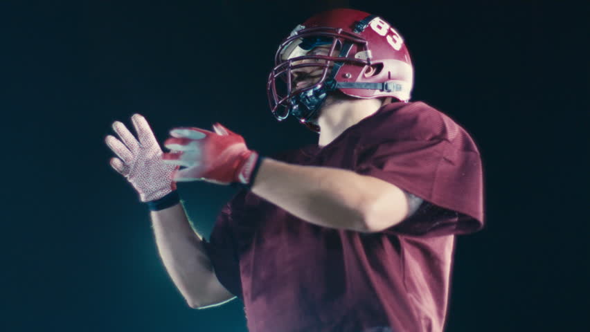 An American football player practicing throwing and catching the ball on a field