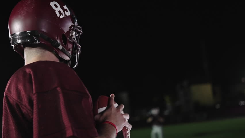 An American football player practicing throwing and catching the ball on a field