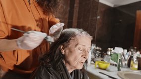 Young woman applying color to a senior woman's gray hair in a bathroom, highlighting a moment of personal care and beauty treatment - Powered by Shutterstock - Get 15% off with code: PIKWIZARD15