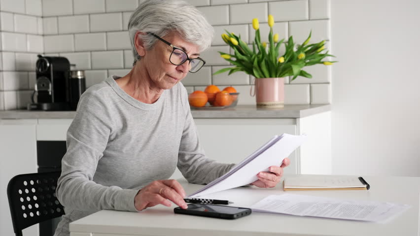 Elderly Woman With Grey Hair Calculating Bill Payments