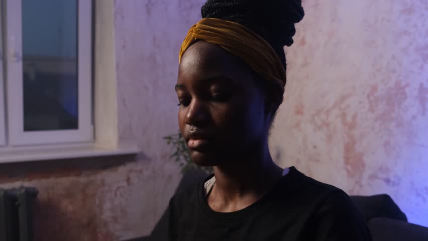 African woman using a dropper to apply serum on her face for skincare