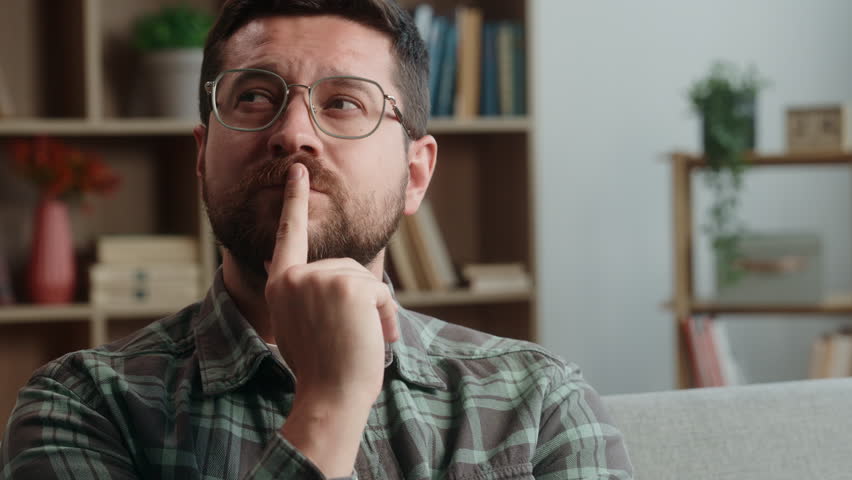 Caucasian man male guy bearded in glasses at home happy smiling pensive thinking thoughtful ponder idea smile think solution decide decision create indoors pondering hesitate unsure search answer glad