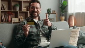 Caucasian man male guy at home happy smiling holding credit bank card buying online internet banking pay purchase shopping buying payment success achieve with laptop computer showing thumb up order - Powered by Shutterstock - Get 15% off with code: PIKWIZARD15