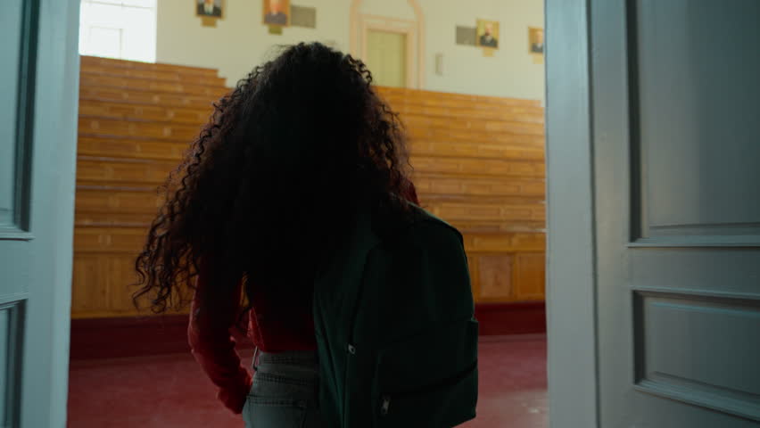 Back view from behind Hispanic student girl Latina woman Caucasian female lady go amazed wonder surprised come in walking in class auditorium university college academy indoors looking around studying