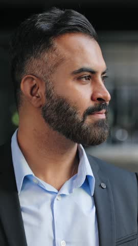 Indian business man Looking out the Office Window smiling to camera