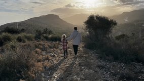 Mother and daughter enjoy a peaceful walk together on a mountain path as the sun sets in slow motion - Powered by Shutterstock - Get 15% off with code: PIKWIZARD15