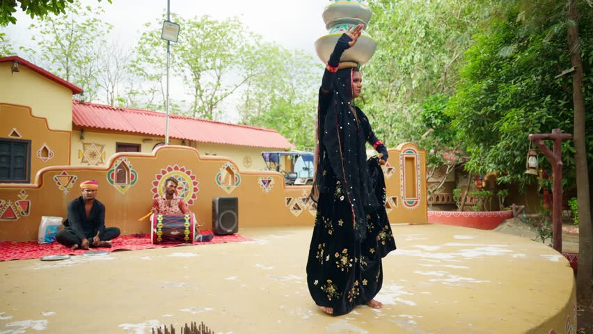 Rajasthani folk dance performance over stage, Traditional Indian dancer balances pot on her head, Rural small entertainment program, Musicians sit nearby playing instruments, Cultural setting outdoor