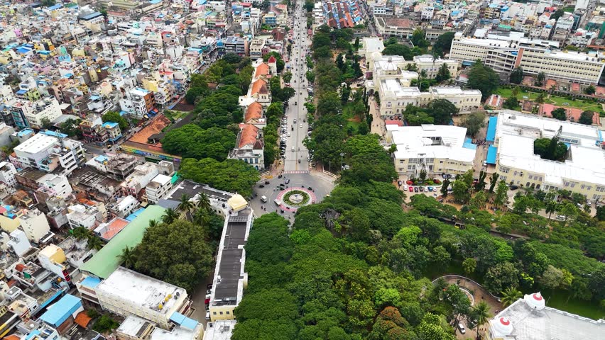 Revealing drone shot of Mysore city in Karnataka. Showing the bustling city center with traffic and revealing the vast cityscape with the Mysore Palace and mountains in the background. India