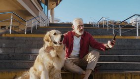 Senior man takes selfie with cute golden retriever sitting on concrete steps. Moment of old dog owner and friendly pet companionship in urban setting - Powered by Shutterstock - Get 15% off with code: PIKWIZARD15