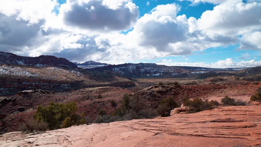 Panning shot showcasing a stunning Landscape of large mountains and clear blue skies in Arches National Park, Utah.