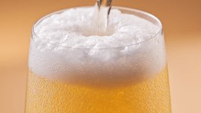 Cold craft light beer pouring to full glass, slow motion close up. Stream wheat malt beverage flowing in clear goblet making dense bubbling foam. Froth heady drink foaming on yellow background - Powered by Shutterstock - Get 15% off with code: PIKWIZARD15