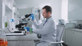 Shot of male scientist holding samples in hands and looking through microscope. Young man in lab coat using modern equipment at workplace in laboratory. Test. Science and medicine concept. Healthcare - Powered by Shutterstock - Get 15% off with code: PIKWIZARD15