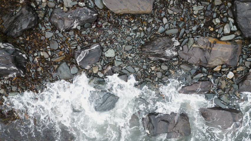Rocky shoreline with waves crashing on colorful stones in Peaks Island, Portland, Maine