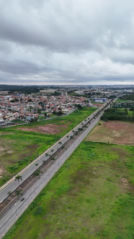 Vertical aerial view of Avenida Mário Covas Júnior in Arujá, São Paulo, showing traffic, vehicles, and the surrounding urban landscape, highlighting the main road of the city