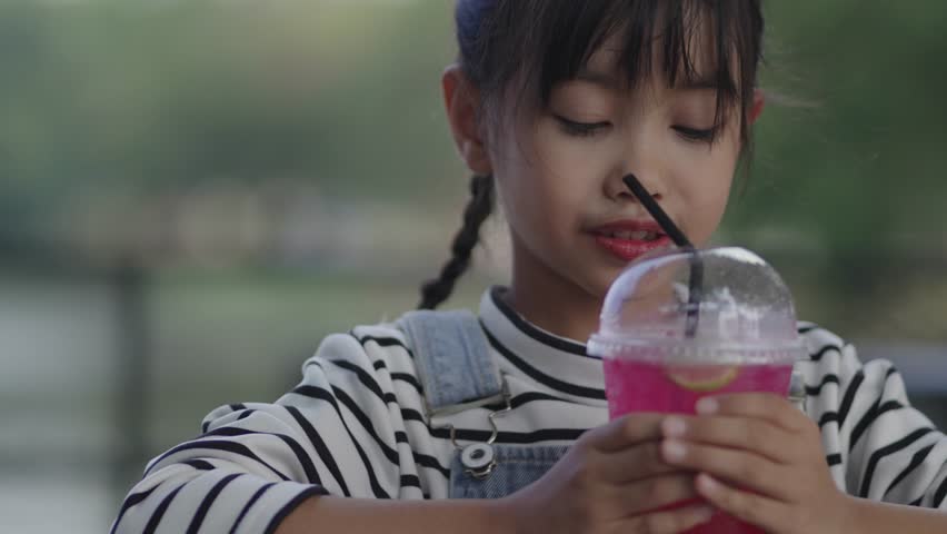 A girl is drinking fruit juice, feeling refreshed in the garden.