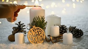 Female hand lights festive Christmas candles with a match. Merry Christmas! Christmas greeting card. White burning candles and Christmas decoration on snow and lights background. - Powered by Shutterstock - Get 15% off with code: PIKWIZARD15