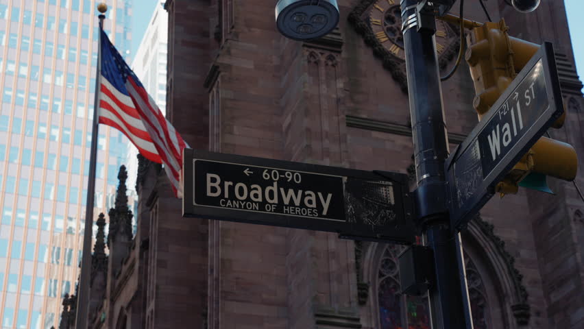 Broadway and Wall St street sign, New York, USA. Wall Street and Broadway. Taxi cars street, a busy tourist intersection of commerce Advertisements and a famous street of New York City and US