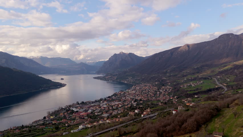 Aerial drone views of Lake Iseo’s serene waters surrounded by lush mountains at sunset.