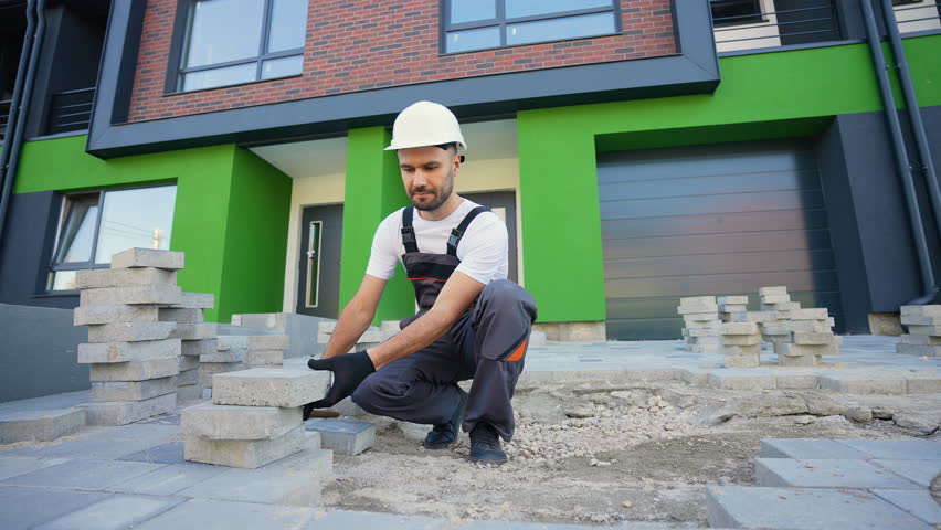 Skilled Worker Laying Paving Stones with Precision Tools