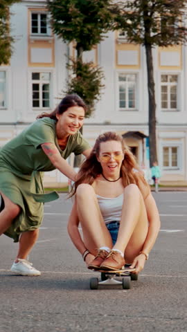 Cool Young Girls and Guy Longboards and Skateboards Through Stylish Hip Cultural Part of the City. Skateboarding Down the Road in the Hipster District. Concept of love, vintage, woman friendship