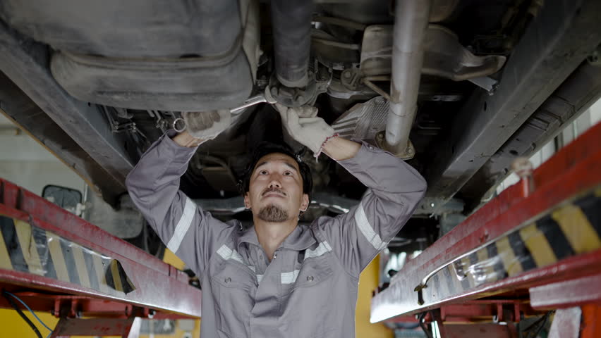 Car service station young asian mechanic man repair auto truck at workshop repairman engineer working underneath lifting vehicle at garage repairing fixing car with wrench tool automobile maintenance