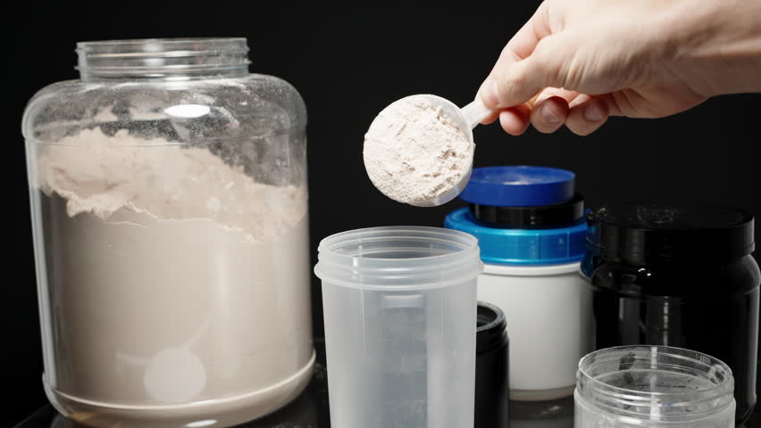 Athlete scooping Protein Powder into the shaker bottle, ready to mix for a post-workout nutrition boost. Slow motion.