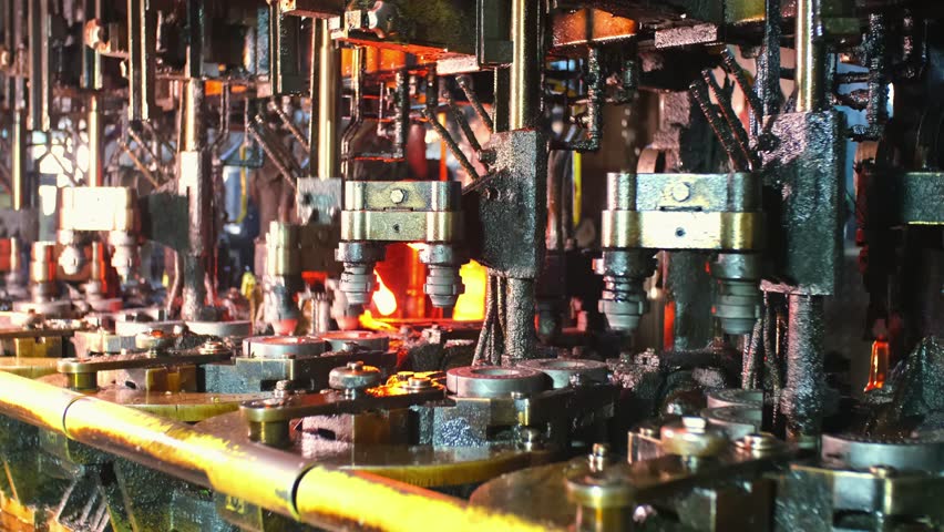 Glass factory, production of glass containers. Molten glass is blown into molds. Robotics in industry. Modern technologies, robotic machines produce products. Technological work at the plant.