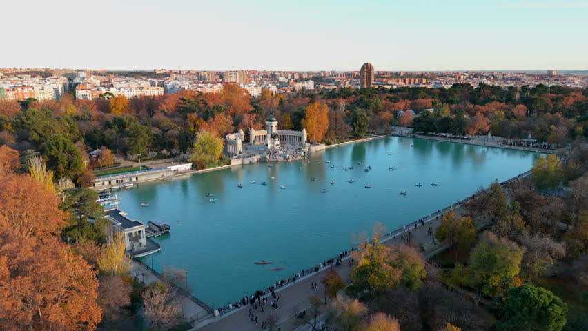 Stunning aerial view of El Retiro Park, highlighting its serene waters surrounded by vibrant autumn colors that beautifully paint the landscape in the heart of Madrid, Spain. Europe