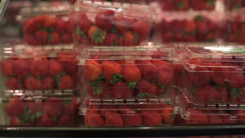 stacked plastic containers filled with vibrant red strawberries, displayed in grocery store. Ideal for themes of fresh produce, healthy eating, and retail. Fresh strawberries in plastic containers