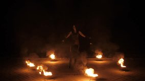 A woman fire-juggler, twirling long flaming cords in her hands. A nighttime circus act featuring fire. A pyrotechnic display. Fire-juggling. Slow motion. - Powered by Shutterstock - Get 15% off with code: PIKWIZARD15