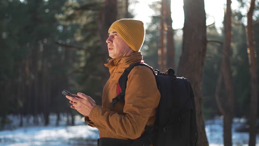 tourist on vacation uses smartphone to improve his trip in forest park. smartphone is in hand of tourist who is going on trip through forest park. Nature is calling tourist uses smartphone to travel.