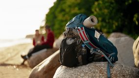 Tourists resting on lake shore in sunset time, closeup of backpack on stone. Traveling and tourism in summer and autumn season, unity of human and nature, backpackers visiting national park, hiking - Powered by Shutterstock - Get 15% off with code: PIKWIZARD15
