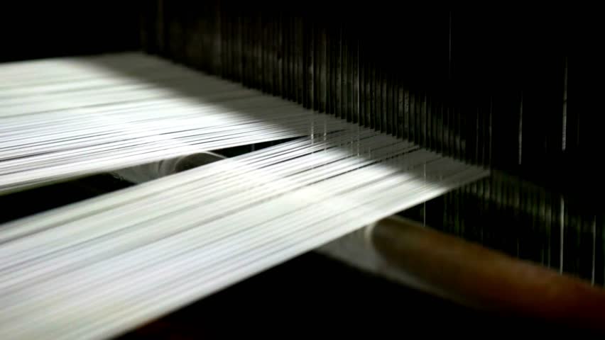 Weaving loom at a textile factory, closeup. industrial fabric production line Spinning factory, production of fabrics, thread of silk, linen, and synthetics